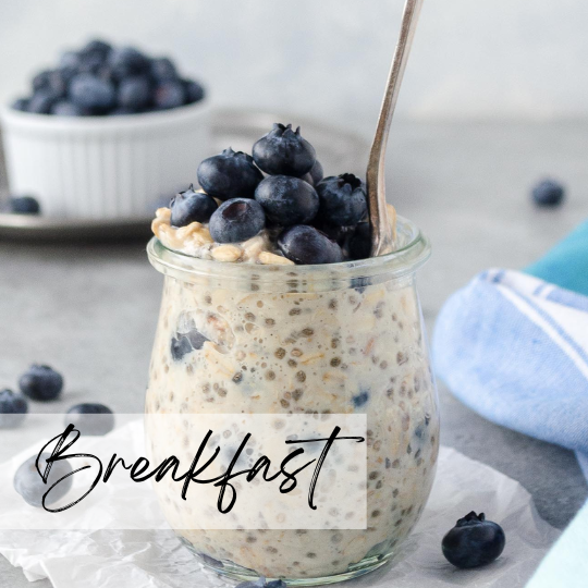A woman in athletic wear sitting on a yoga mat indoors, smiling.
