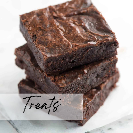 A woman in athletic wear sitting on a yoga mat indoors, smiling.